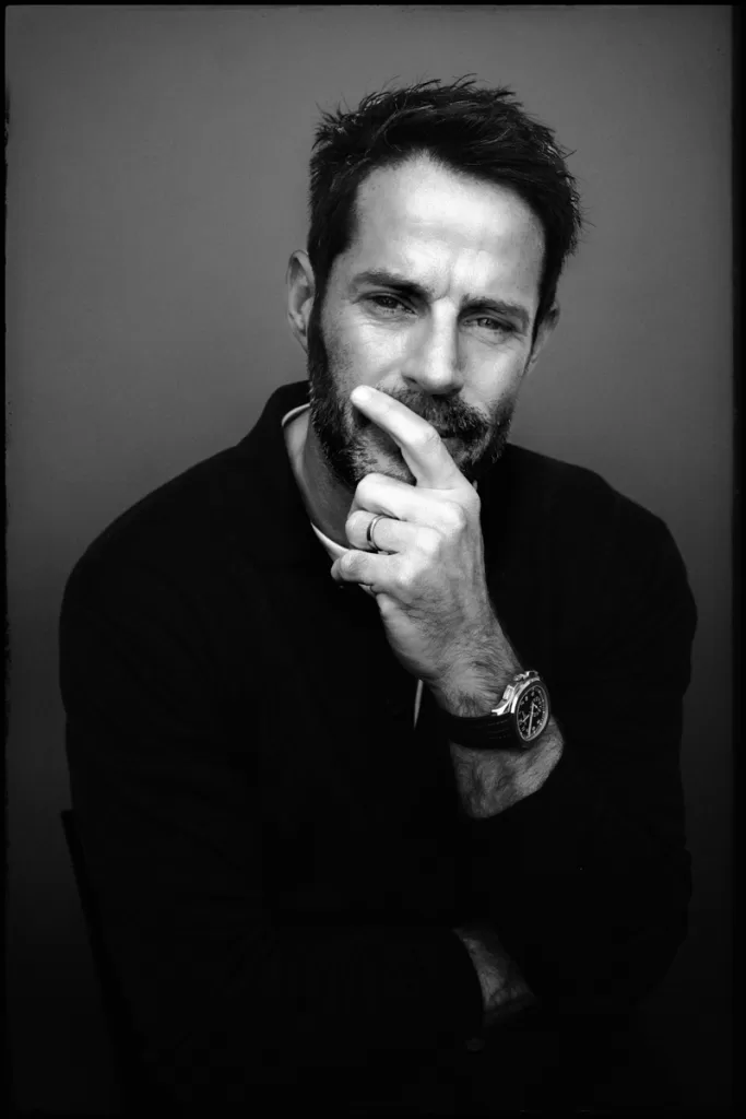 A portrait of Jamie Redknapp holding his face with one hand and looking directly into the camera.