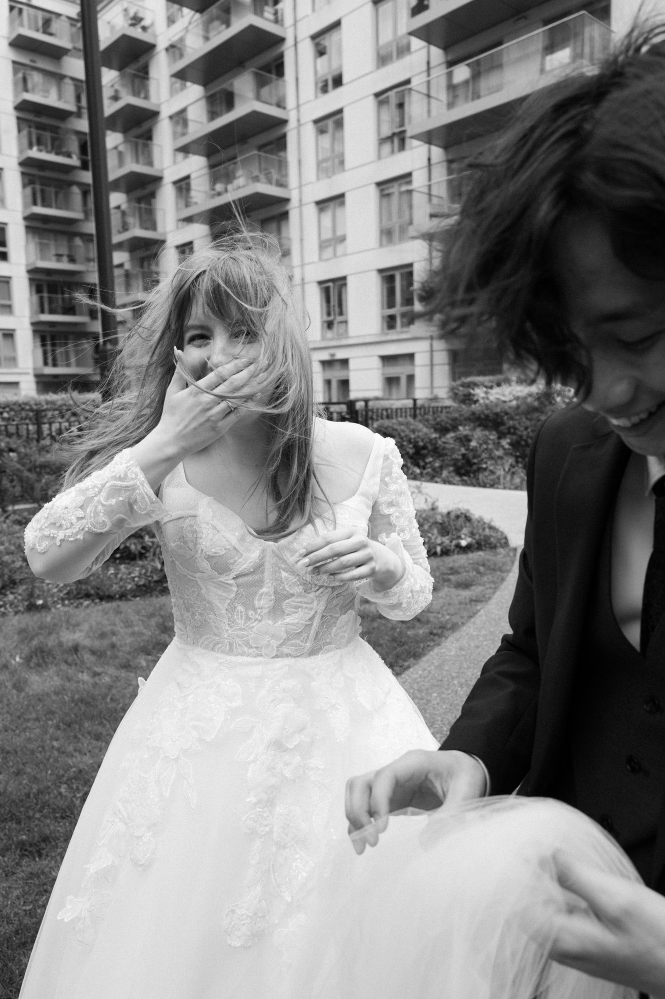 A young couple laugh together as the groom catches the brides veil.