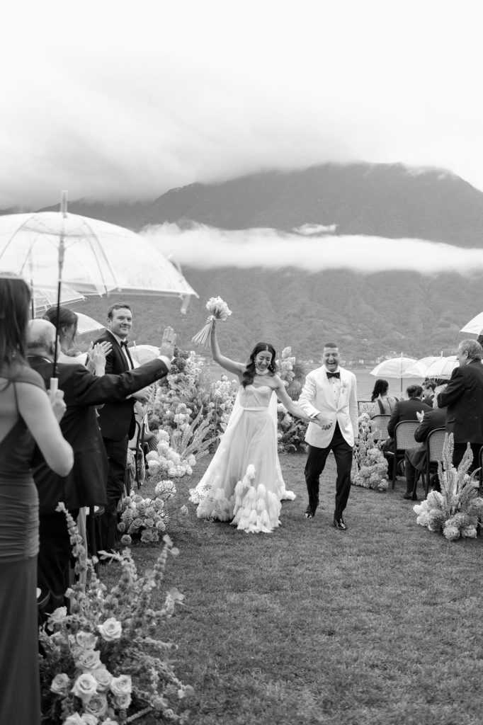 Walking down the aisle following their Villa Balbiano Wedding in Lake Como Alex, the bride, can be seen throwing her bouquet into the air.